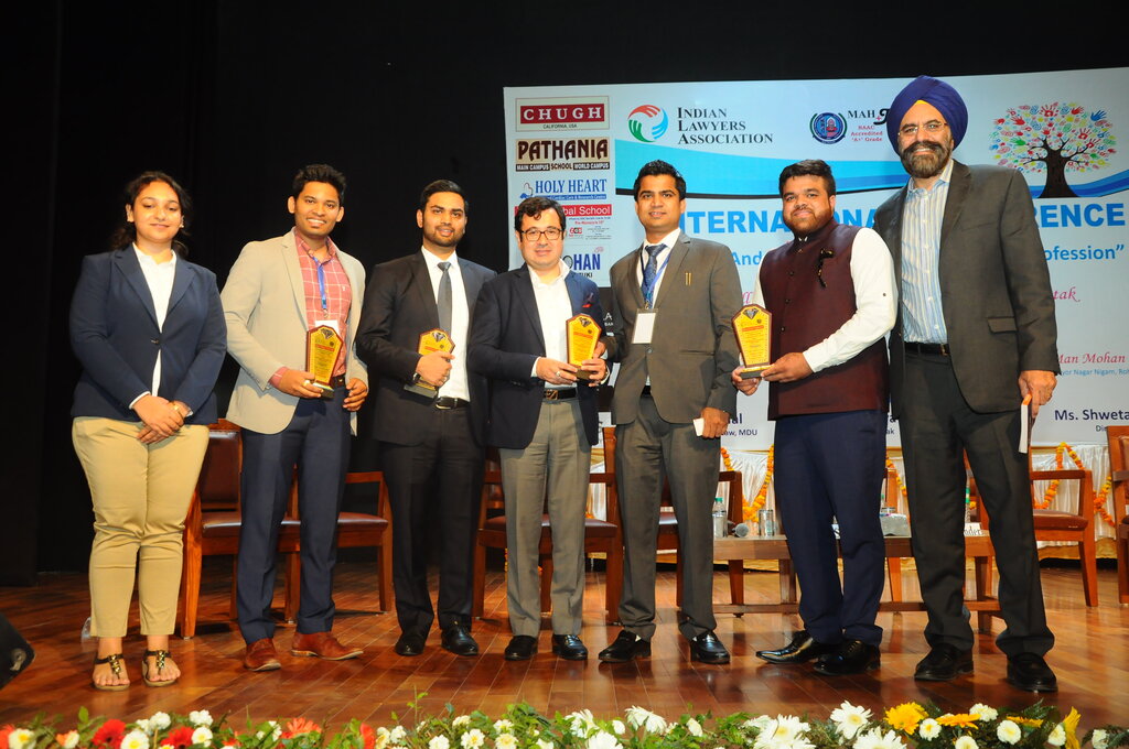 Advocate Naveen Arya as a chair on stage at the Indian Lawyers Association International Conference with fellow panellists holding awards